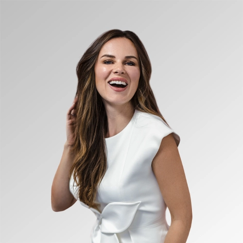 Joyful woman in a white dress laughing against a soft gradient background.