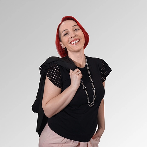 Confident woman with red bob hairstyle smiling, wearing a chic black top and blazer.