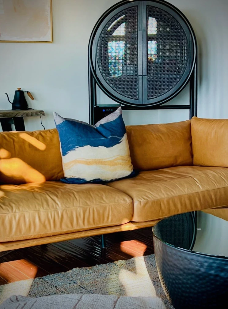 Stylish living room featuring a leather sofa, decorative pillows, unique shelving, and a coffee table.