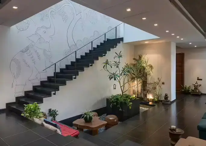 Elegant modern interior with lush plants, featuring a striking staircase and inviting seating area.