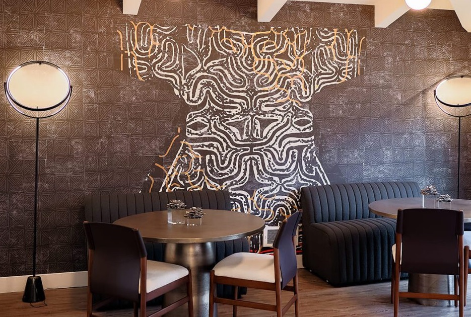 Stylish restaurant interior featuring modern furnishings and an artistic black-and-white mural.