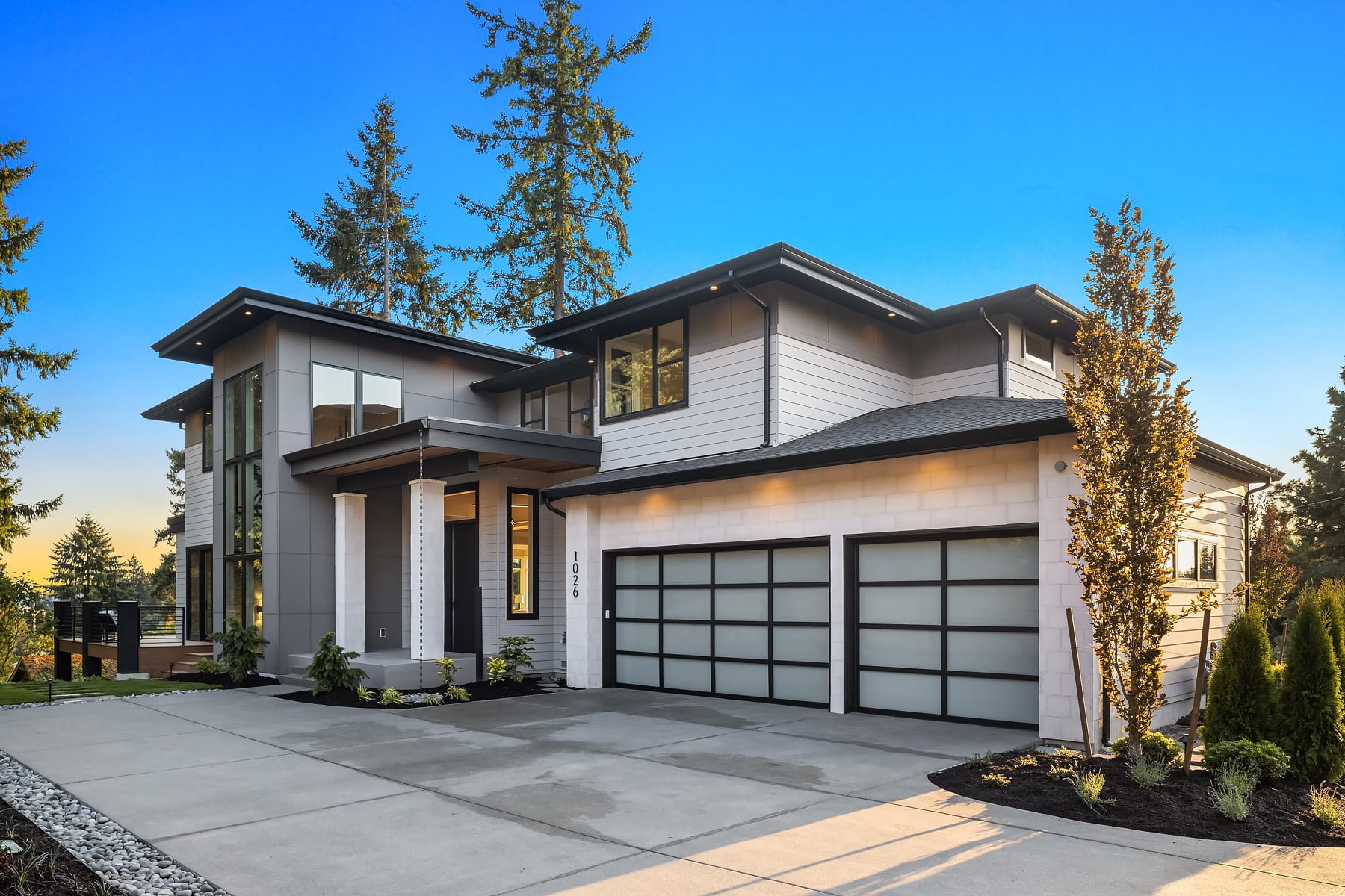 Contemporary two-story home with sleek design, large windows, and elegant landscaping in a serene setting.