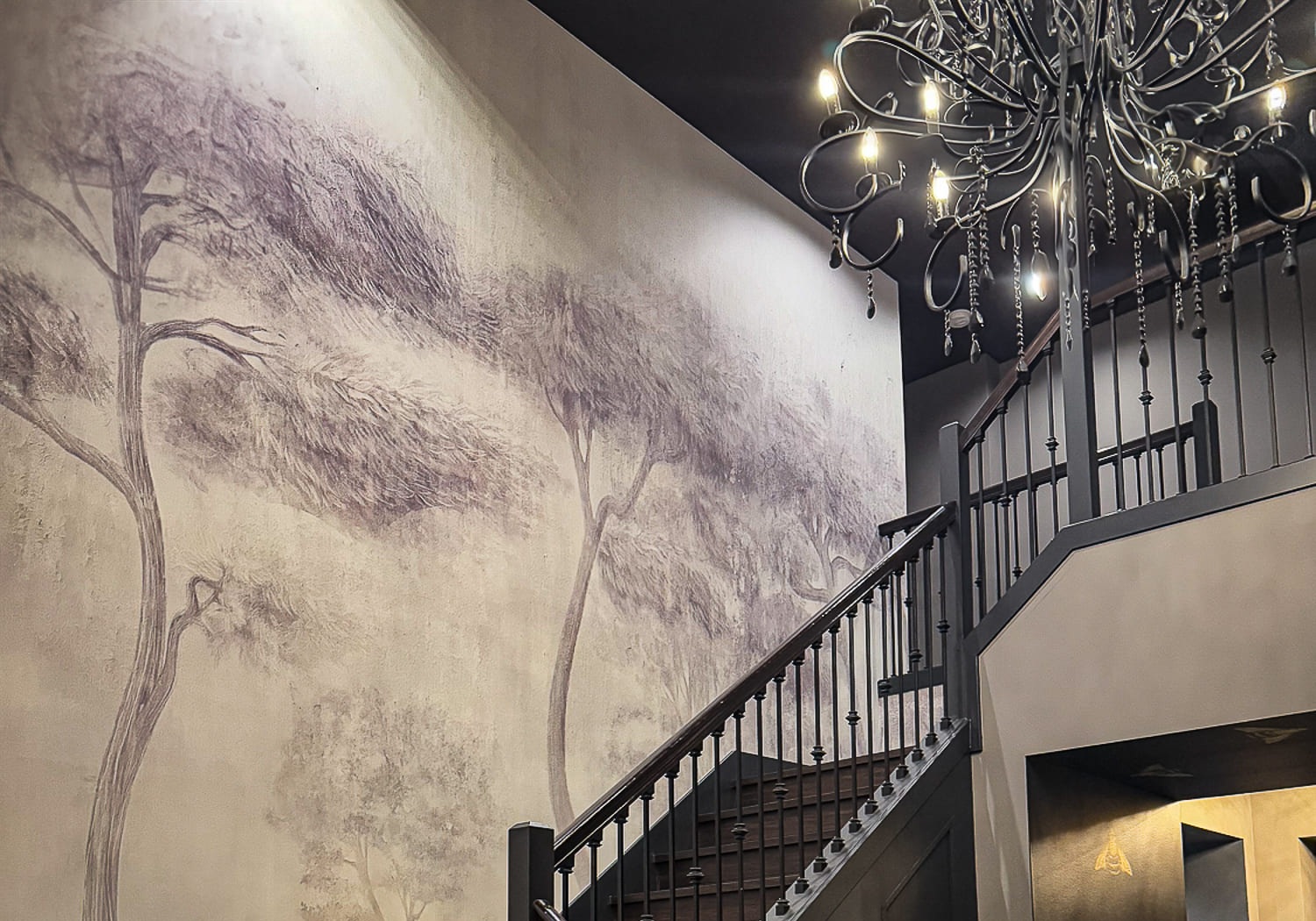 Elegant staircase with mural art and chandelier in contemporary interior design.