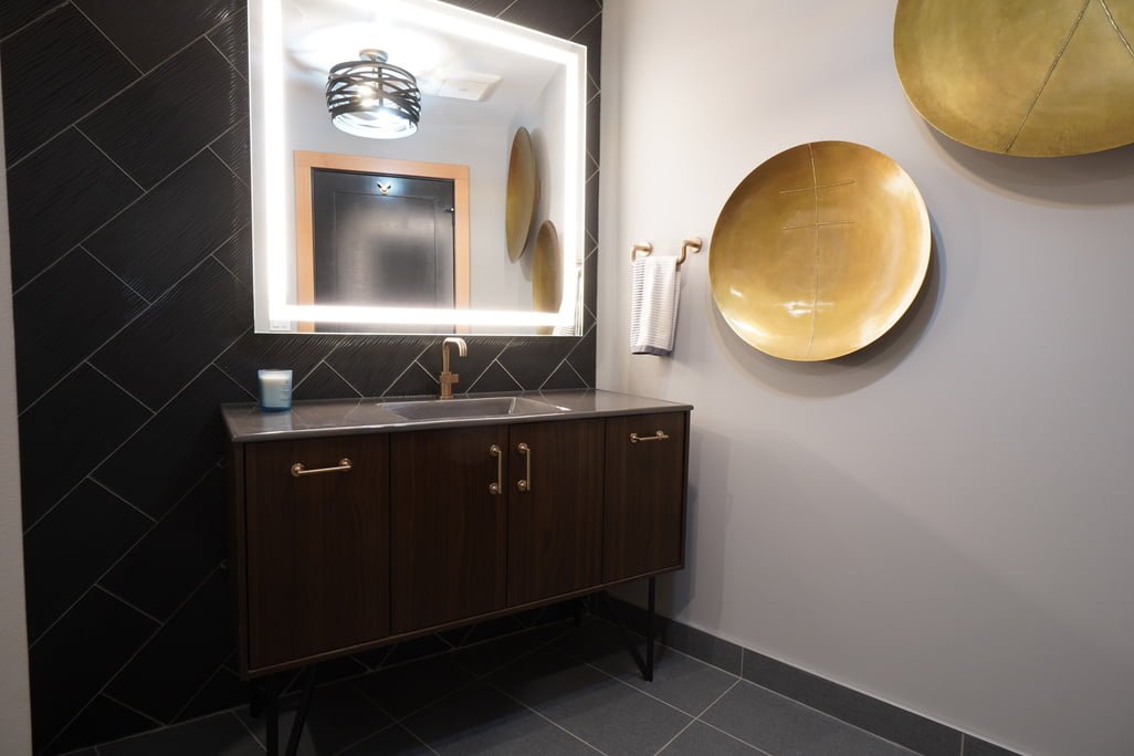 Elegant modern bathroom design featuring dark tiles, sleek cabinetry, and stylish gold accents.