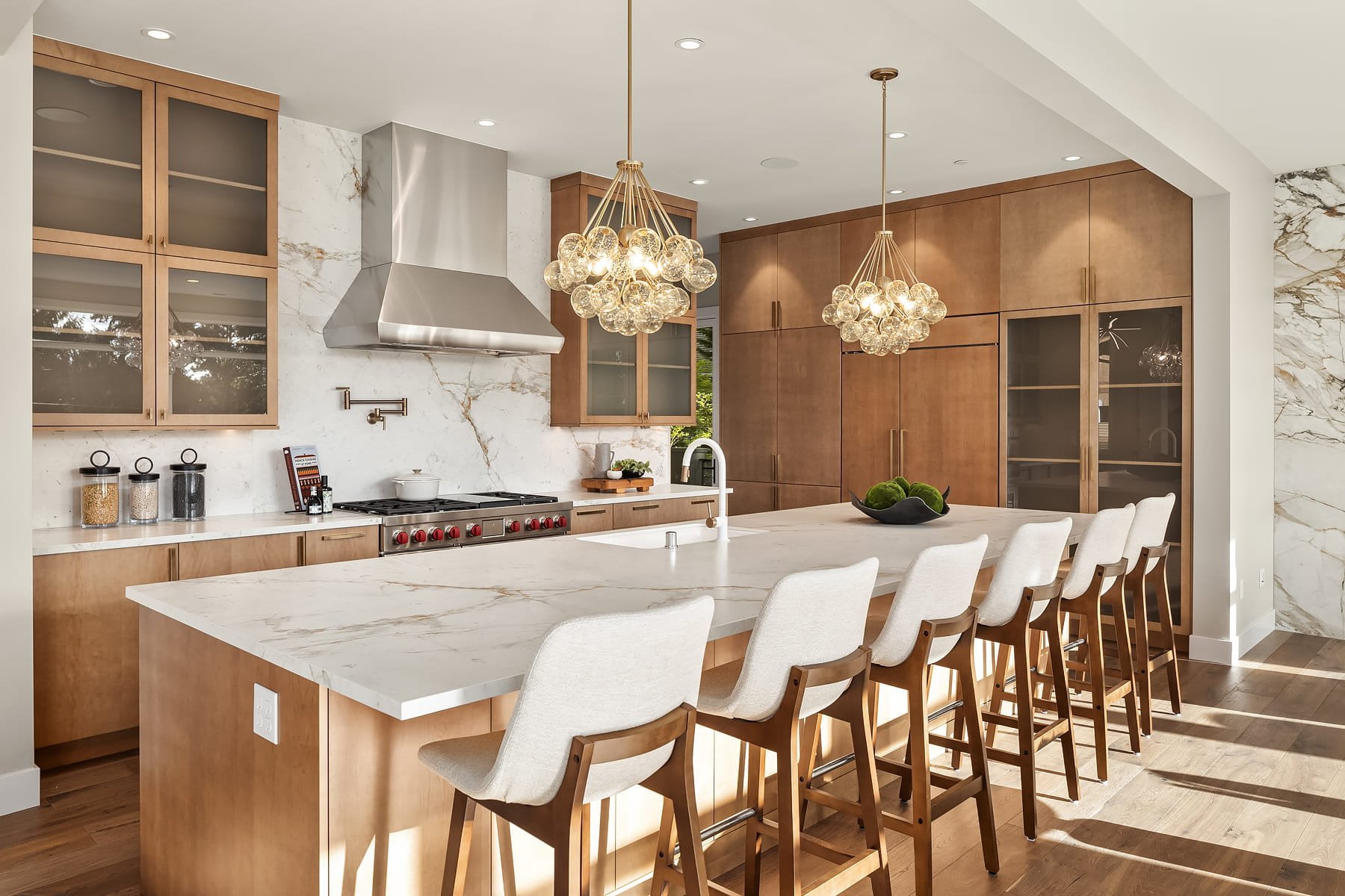 Elegant modern kitchen featuring warm wood accents, marble countertops, and stylish seating.