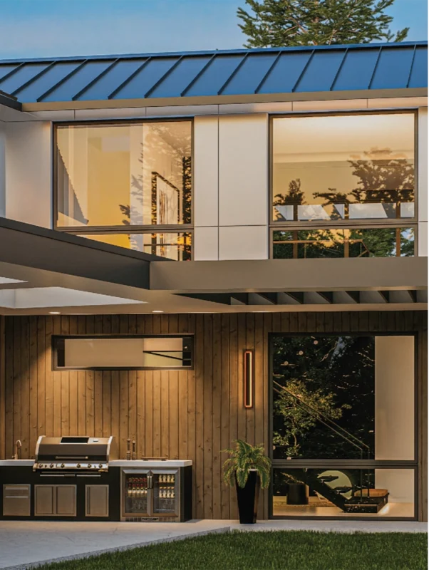 Contemporary home with outdoor kitchen, seamless indoor-outdoor flow, surrounded by lush greenery.