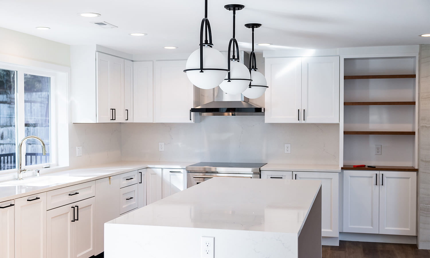 Bright modern L-shaped kitchen with white cabinetry and stylish pendant lighting.