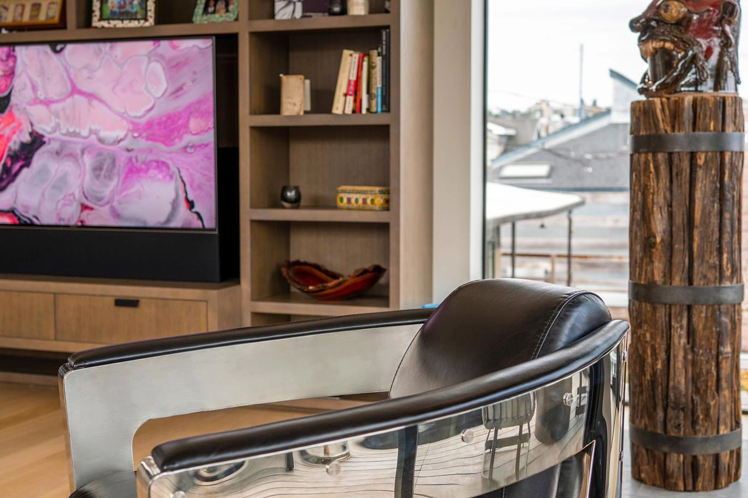 Modern living room with stylish armchair, vibrant art, and unique wooden sculpture.