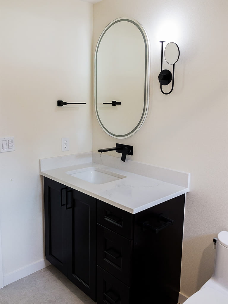 Stylish minimalist bathroom featuring a sleek black vanity and elegant lighting accents.