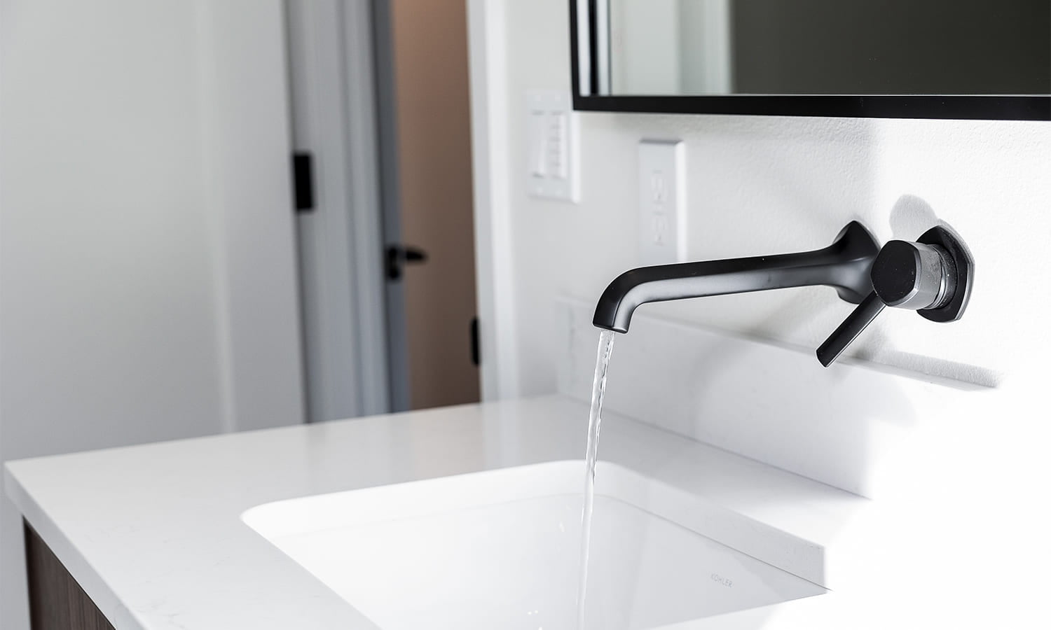 Minimalist bathroom sink with black faucet, sleek mirror, and modern design elements.