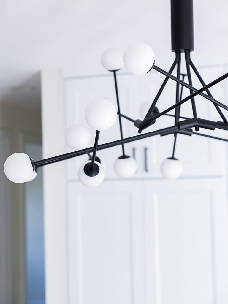 Sleek minimalist chandelier with geometric design and white glass bulbs in a bright room.