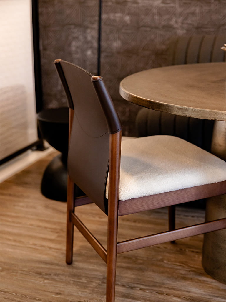 Modern minimalist dining room with elegant wooden chair and round stone table.