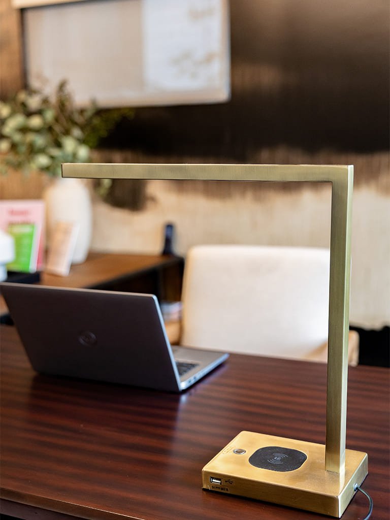 Stylish gold desk lamp illuminating a contemporary workspace with laptop and plants.