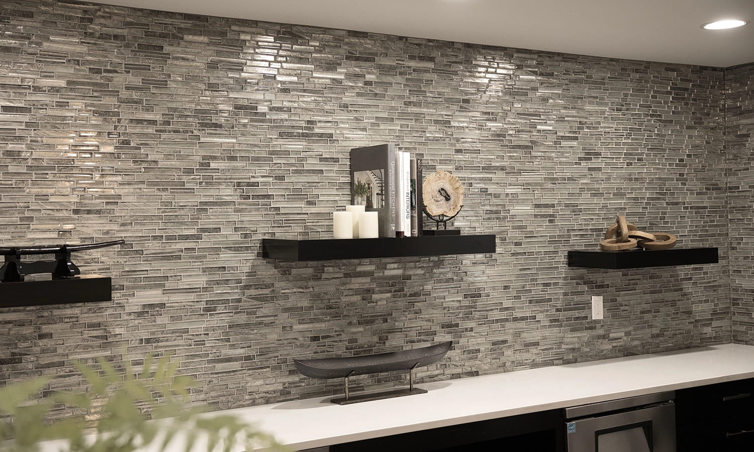 Contemporary kitchen featuring a textured backsplash, sleek countertop, and stylish floating shelves.