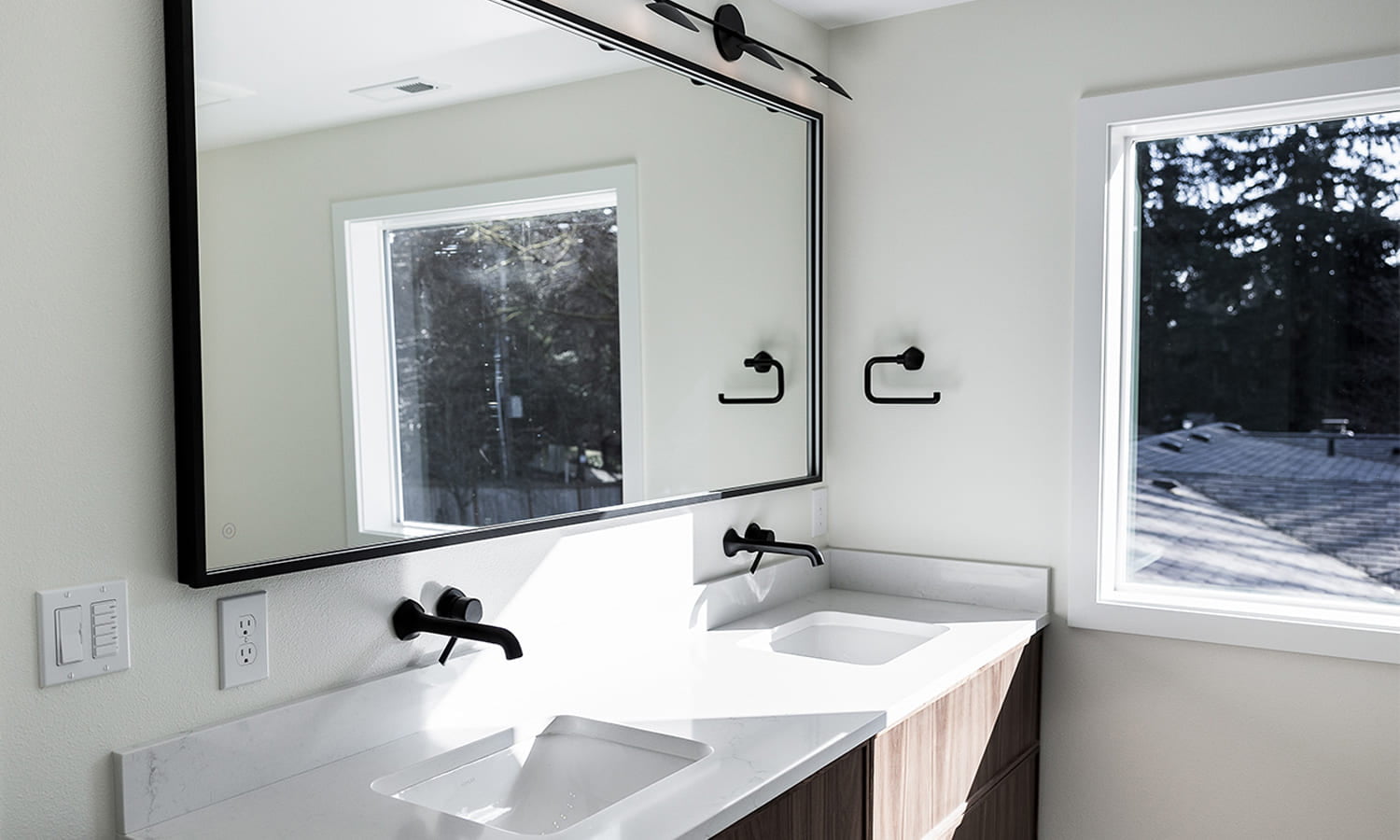 Sleek modern bathroom featuring natural light, warm wood accents, and minimalist design elements.