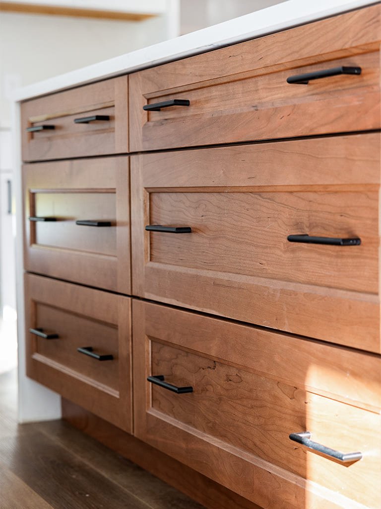 Stylish wooden drawers with sleek black handles in a modern kitchen setting.