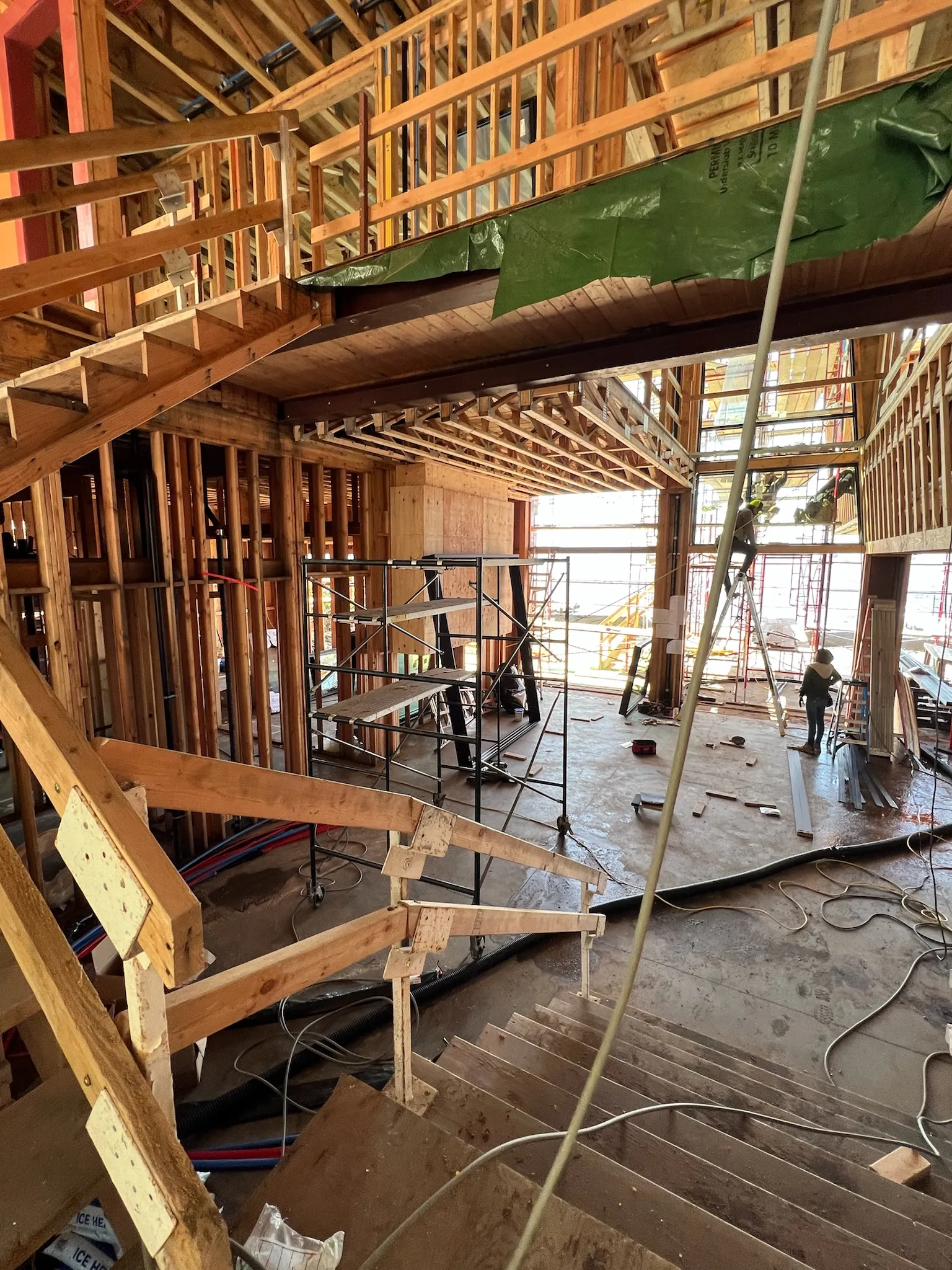 Active construction site showcasing progress with wooden stairs, scaffolding, and natural light.