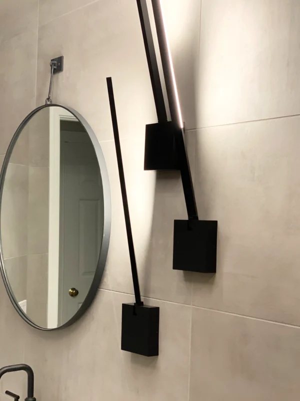 Sleek modern bathroom featuring a round mirror and artistic geometric lighting fixture.