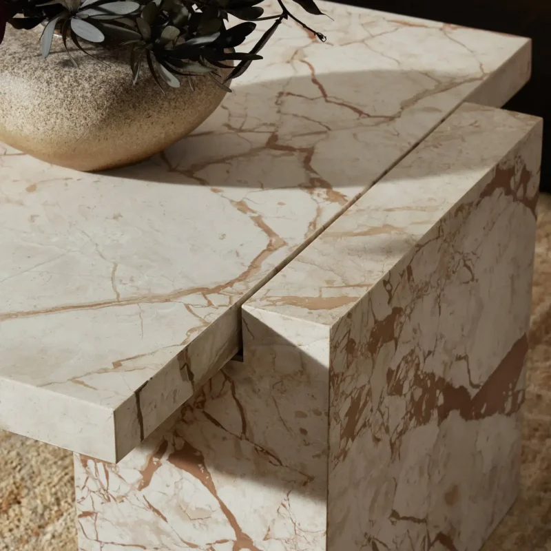 Modern geometric marble coffee table with decorative foliage, enhancing elegant indoor aesthetics.