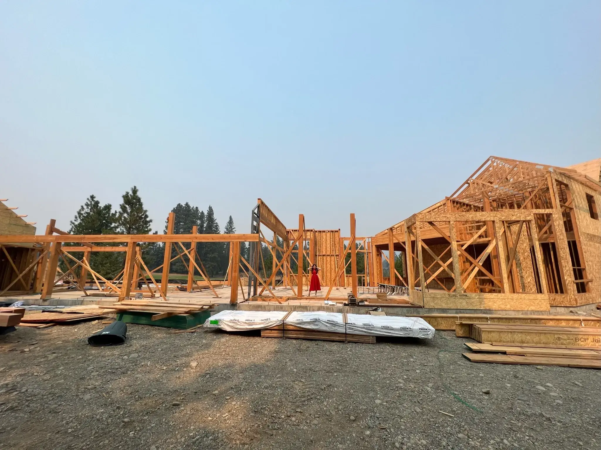 Framing a wooden structure amidst trees at a bustling construction site.