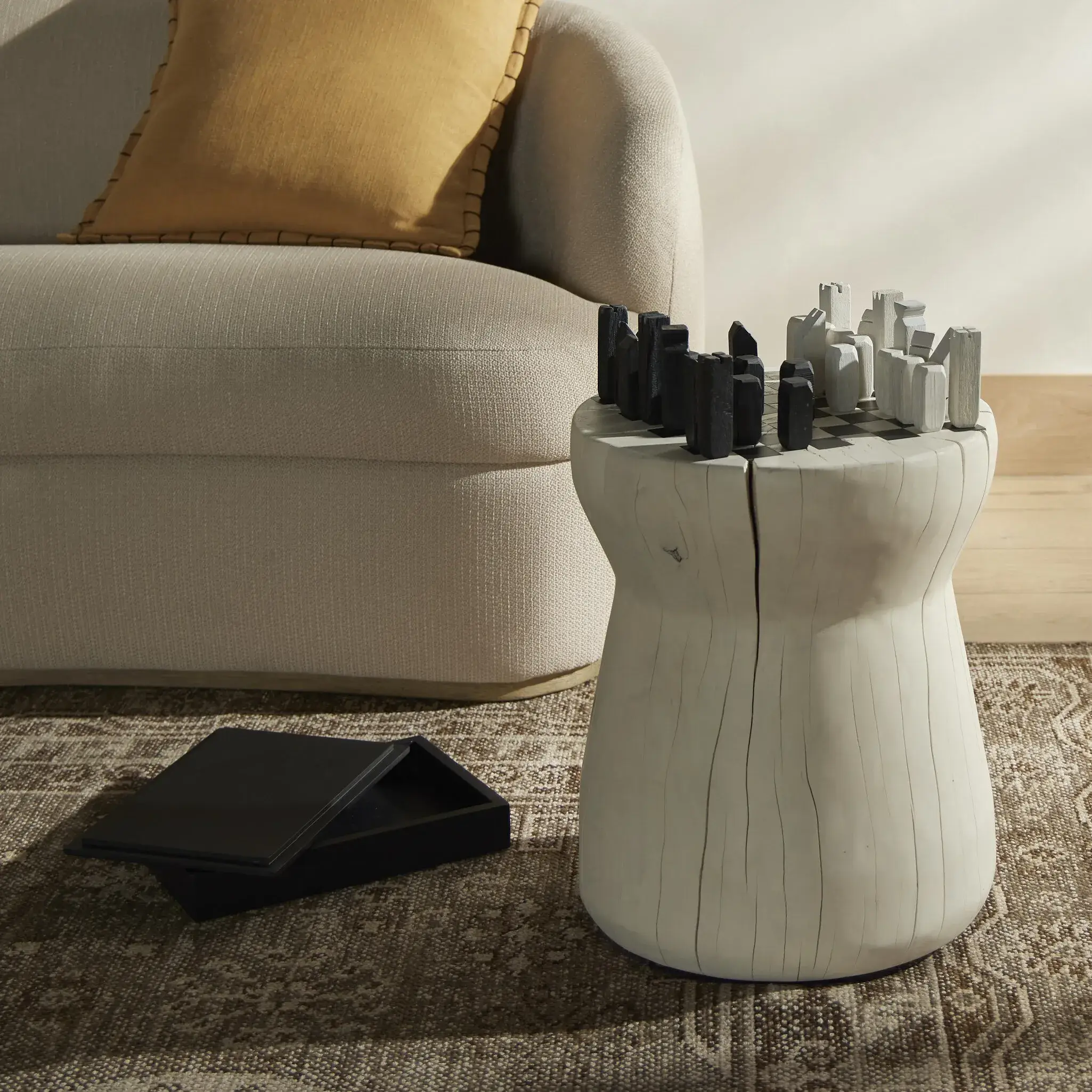 Modern living room featuring a unique cylindrical accent table and cozy beige sofa.