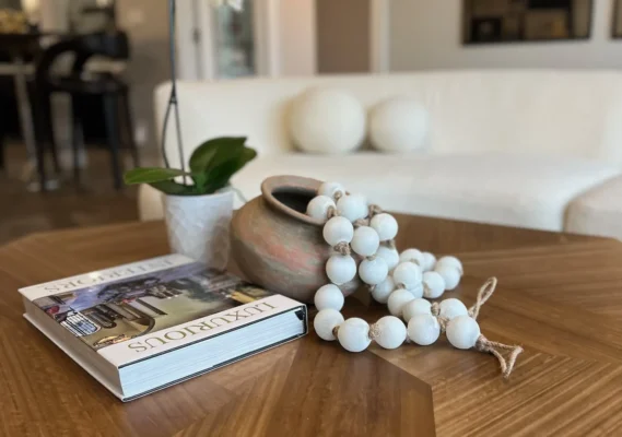 Cozy living room coffee table with stylish decor, including a book, pot, and beads.