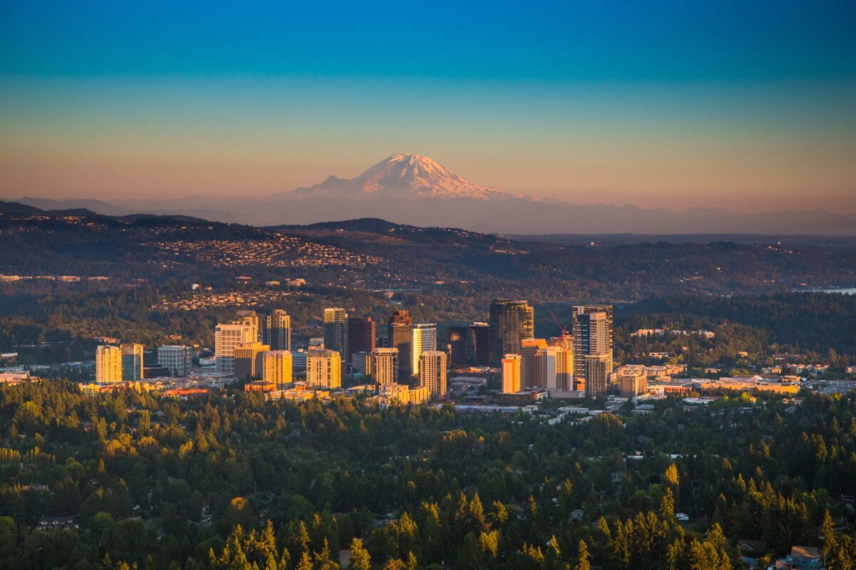 Stunning city skyline with majestic mountain backdrop at sunset, blending urban and natural beauty.