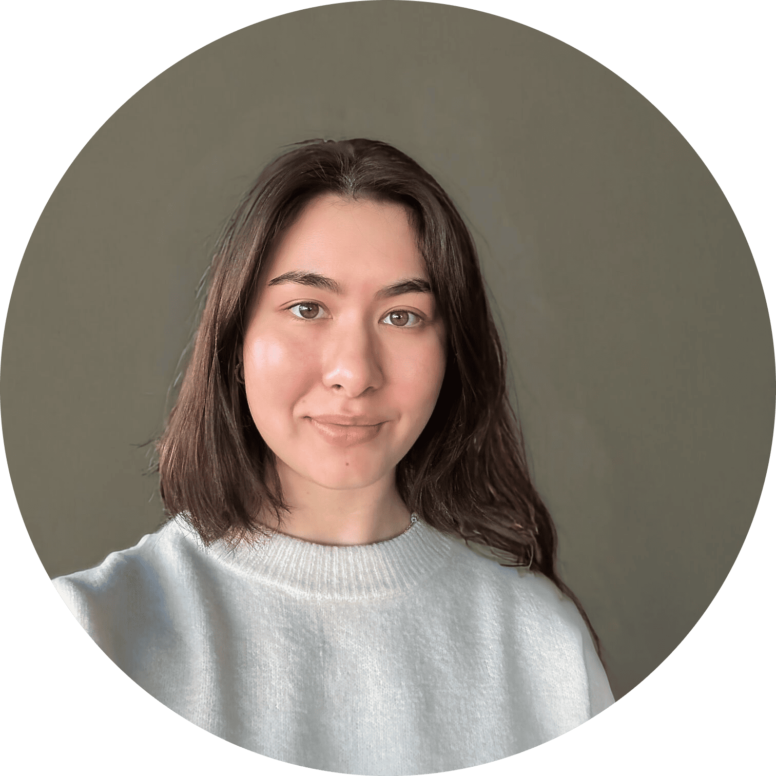 Young woman in a light gray sweater smiles warmly in a soft, neutral portrait.