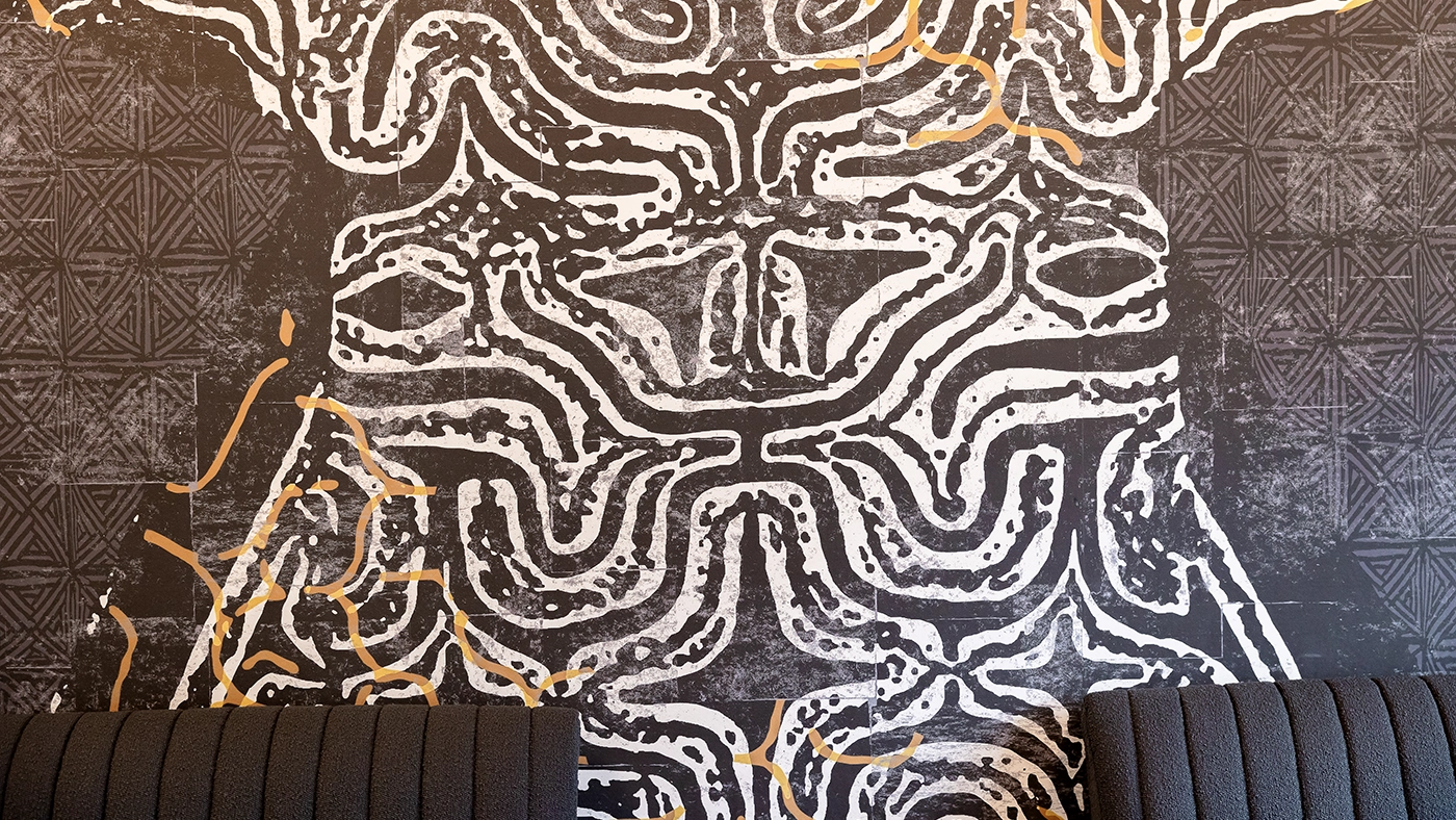 Striking black and white mural with golden accents, enhancing contemporary café decor.