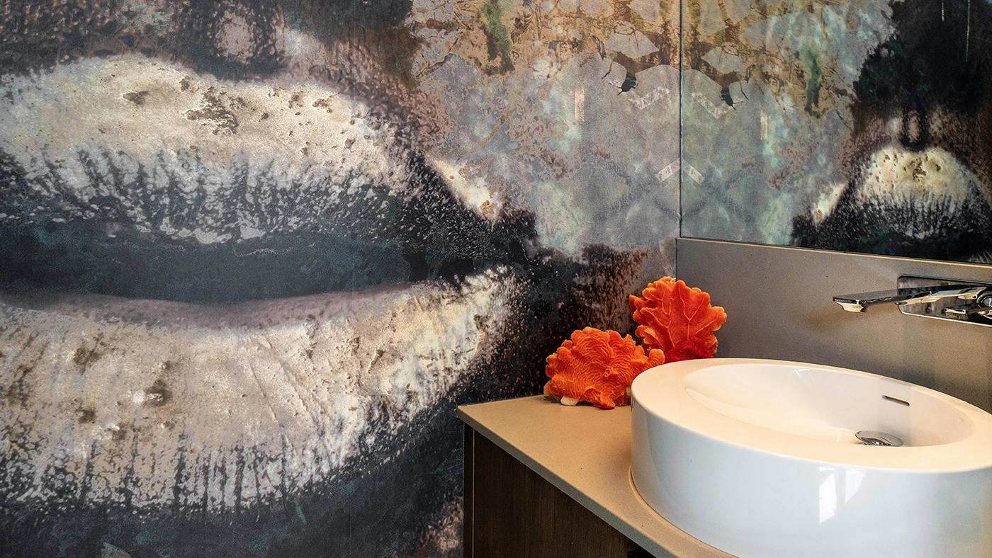 Artistic bathroom mural of lips with modern sink and vibrant coral decor elements.