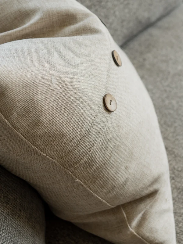 Close-up of a textured beige pillow with wooden buttons, perfect for cozy living spaces.