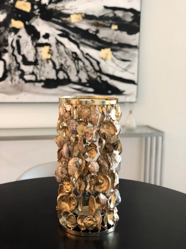 Elegant decorative vase on a black table with abstract art, showcasing natural textures and gold accents.