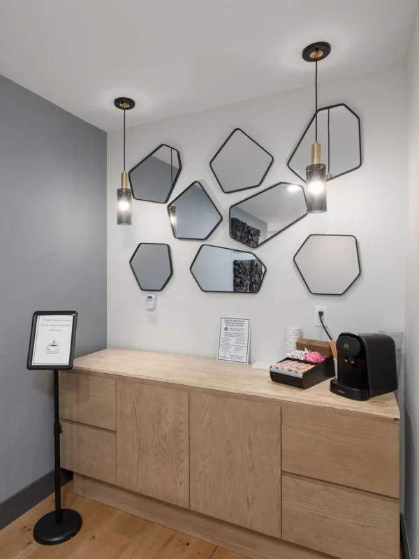 Modern reception area with stylish decor, hexagonal mirrors, warm wood countertop, and inviting ambiance.