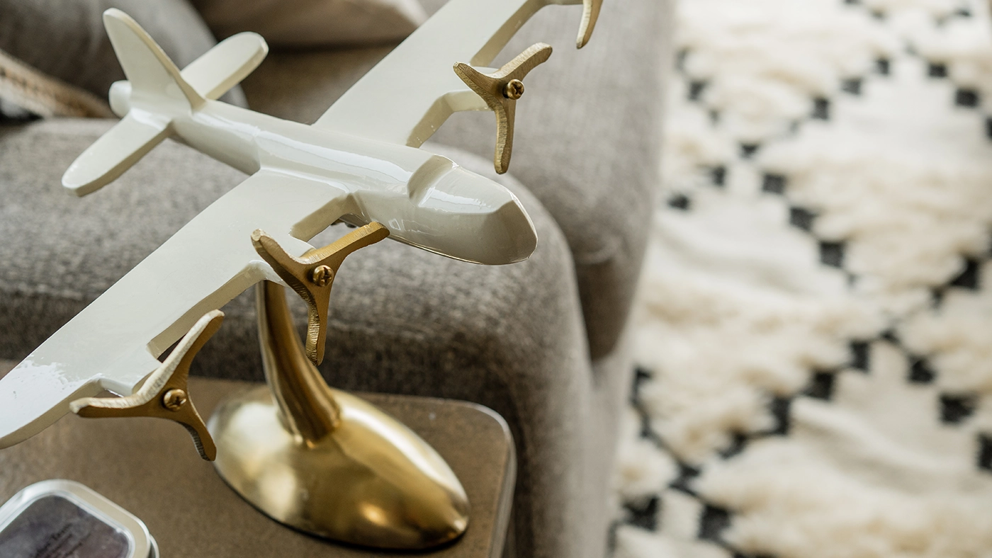 Elegant decorative airplane model in white and gold, showcased on a stylish table.