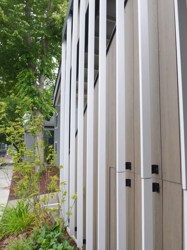 Modern architectural facade featuring wooden panels, sleek stripes, and lush greenery in a cohesive design.