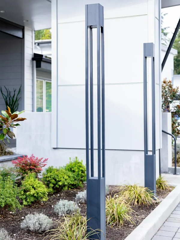 Modern light fixtures enhance landscaped garden next to a sleek minimalist building entrance.