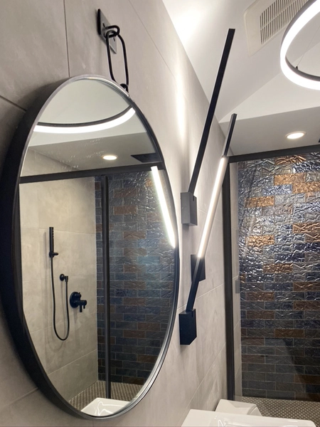 Contemporary bathroom with stylish mirror, warm lighting, and textured wall tiles for a modern design.