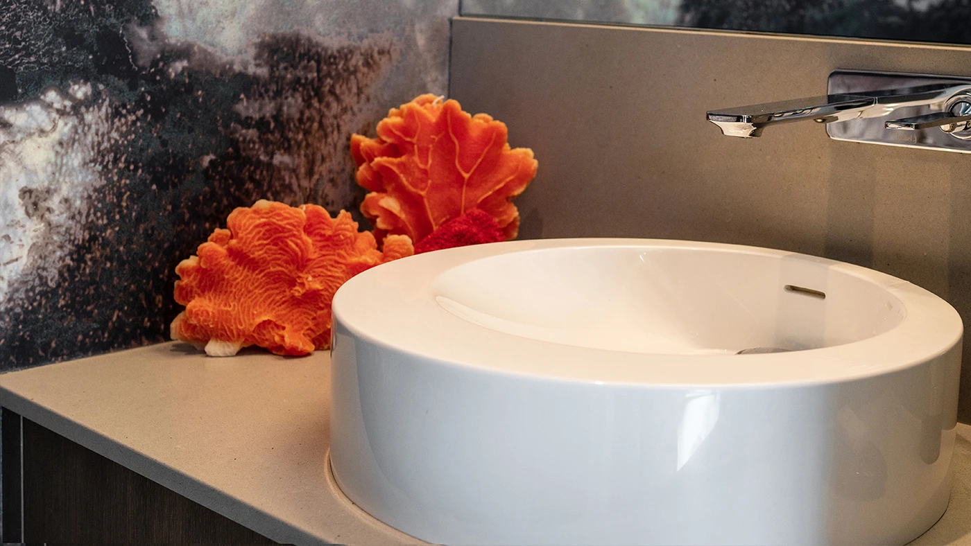 Modern bathroom with a sleek round sink, elegant decor, and textured dark wall design.