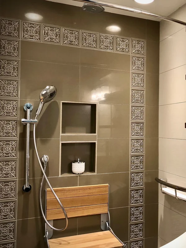 Elegant modern shower with dual showerheads, niche storage, and accessibility features in warm tones.