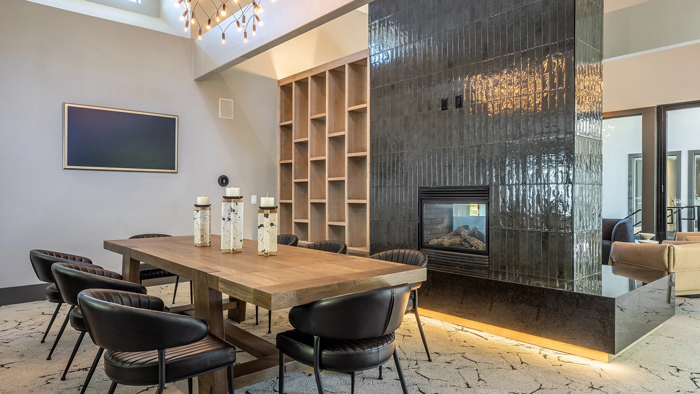 Stylish modern dining area with fireplace, wooden table, and elegant black chairs.