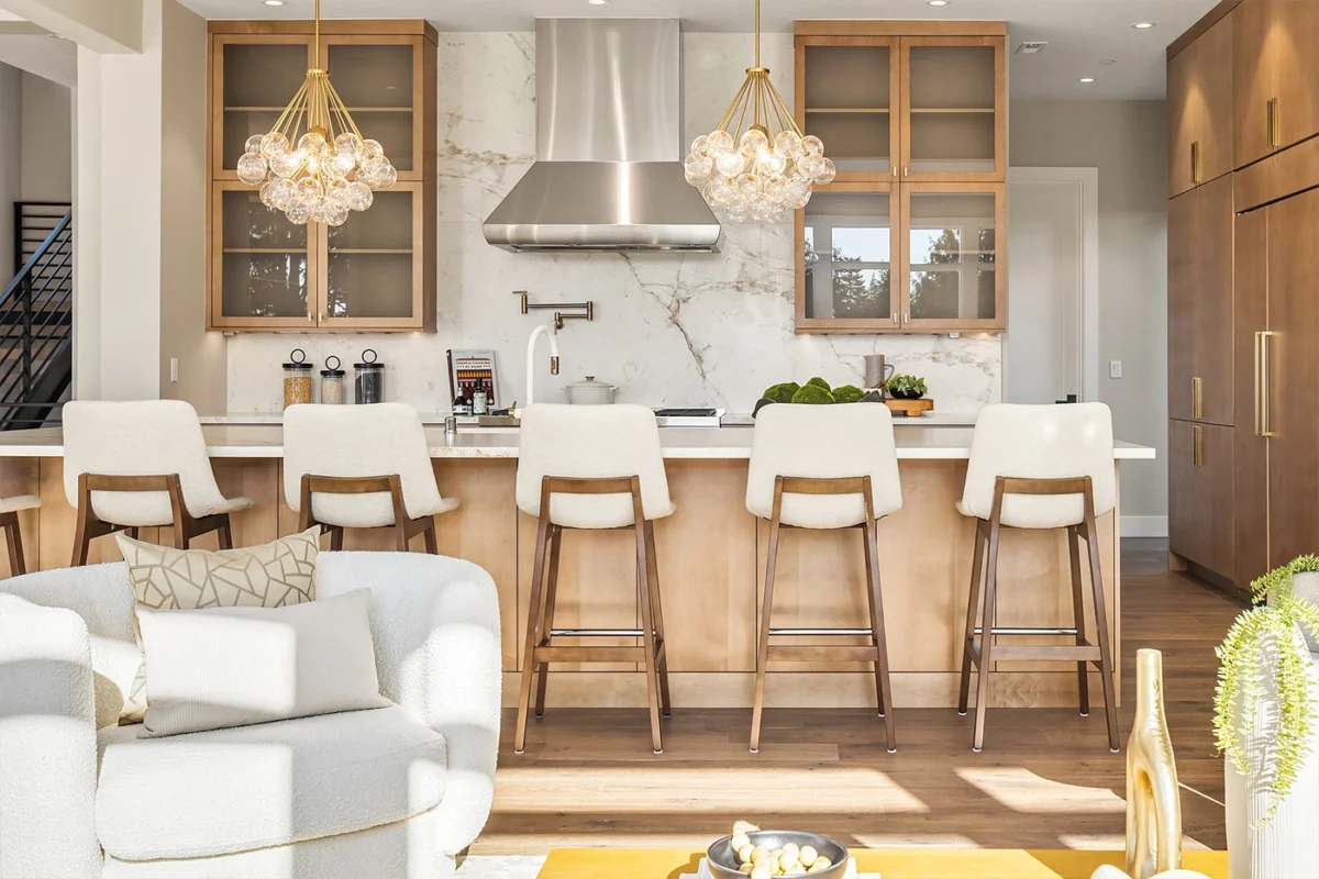 Elegant modern kitchen design with stylish island, marble backsplash, and cozy seating area.