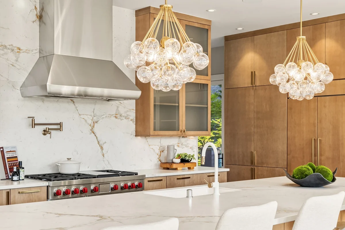 Elegant modern kitchen with marble island, wooden cabinetry, and stylish pendant lighting.