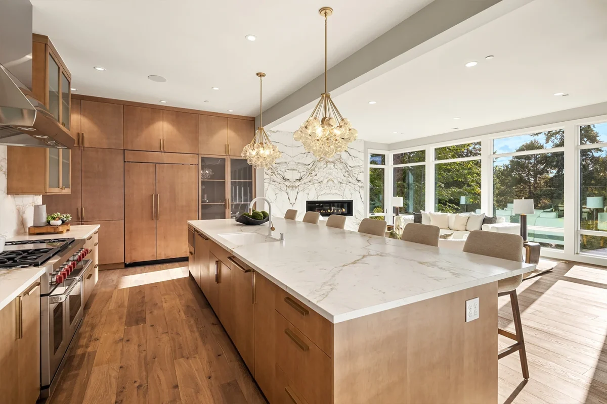 Elegant modern kitchen with wood cabinetry, marble island, and stylish pendant lighting.