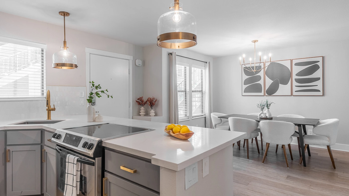 Modern kitchen and dining area featuring elegant design, white countertops, and stylish lighting.