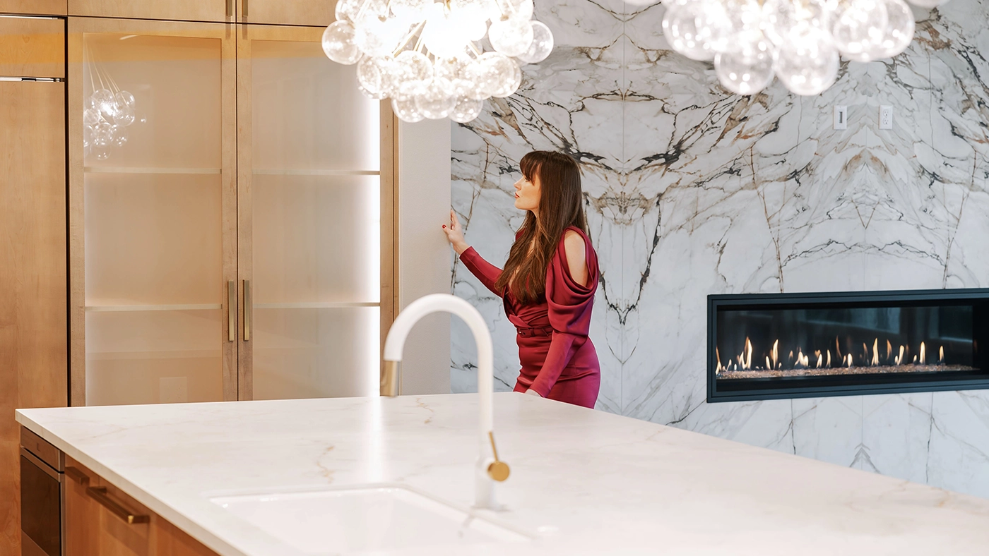 Elegant modern kitchen featuring marble island, light wood cabinetry, and stylish lighting fixtures.