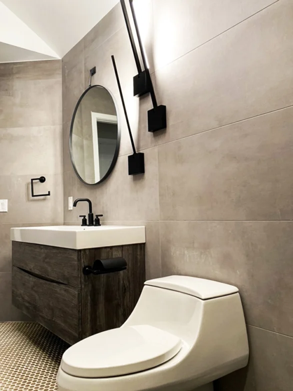 Contemporary minimalist bathroom with gray tiles, wooden vanity, and sleek black fixtures.