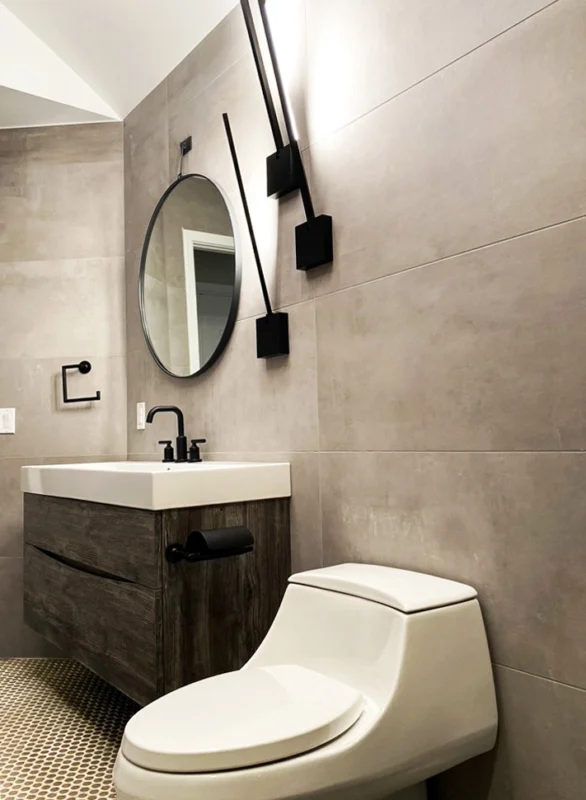 Modern minimalist bathroom design with gray tiles, wooden vanity, and stylish fixtures.