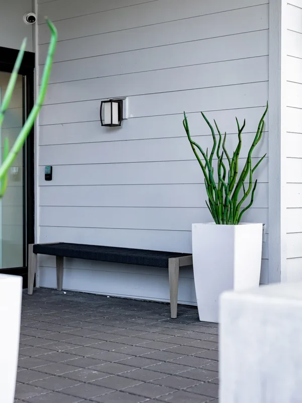 Modern minimalist entryway with elegant bench, white planter, and stylish lighting for a welcoming atmosphere.