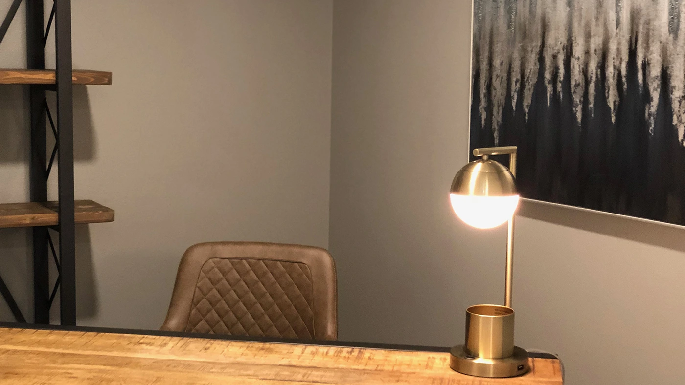 Cozy modern office setting with a stylish wooden desk, sleek chair, and decorative shelving unit.