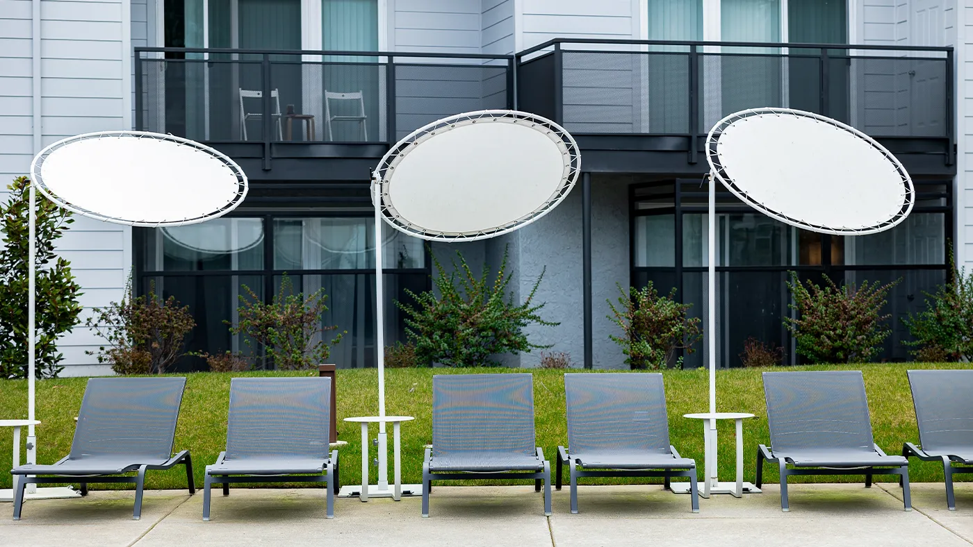 Modern outdoor lounge area with sleek chairs, canopies, and a serene poolside backdrop.